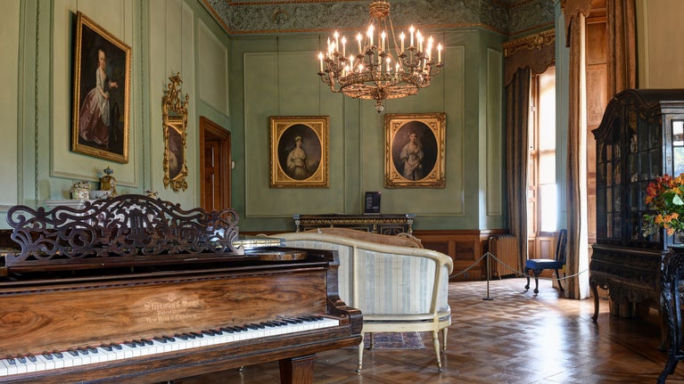A view of the Drawing Room from the conservatory entrance with the Steinway on the left, the seating in the middle and the chandelier overhead.